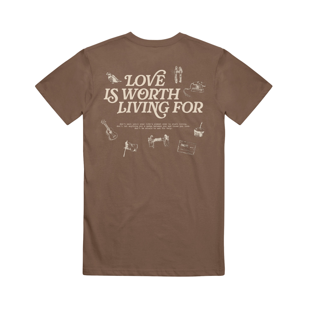 Joshua Bassett Brown Espresso Tee features "Love Is Worth Living For" in bold white text on the back, accented by small white guitar, camera, and cassette tape illustrations.