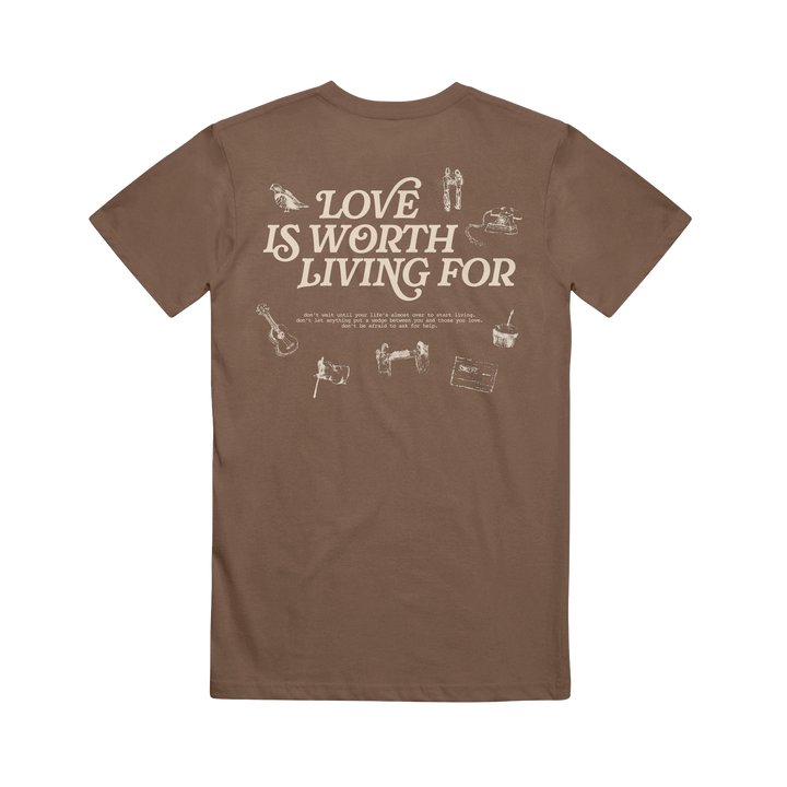 Joshua Bassett Brown Espresso Tee features "Love Is Worth Living For" in bold white text on the back, accented by small white guitar, camera, and cassette tape illustrations.