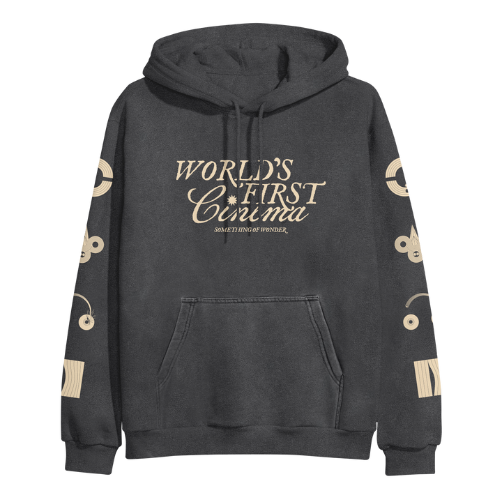 A dark gray World's First Cinema pullover hoodie with cream text "WORLDS FIRST CINEMA SOMETHING OF WONDER" on the front, abstract cream graphics on both sleeves, a front pocket, and drawstrings. Midweight by Independent Trading Company.