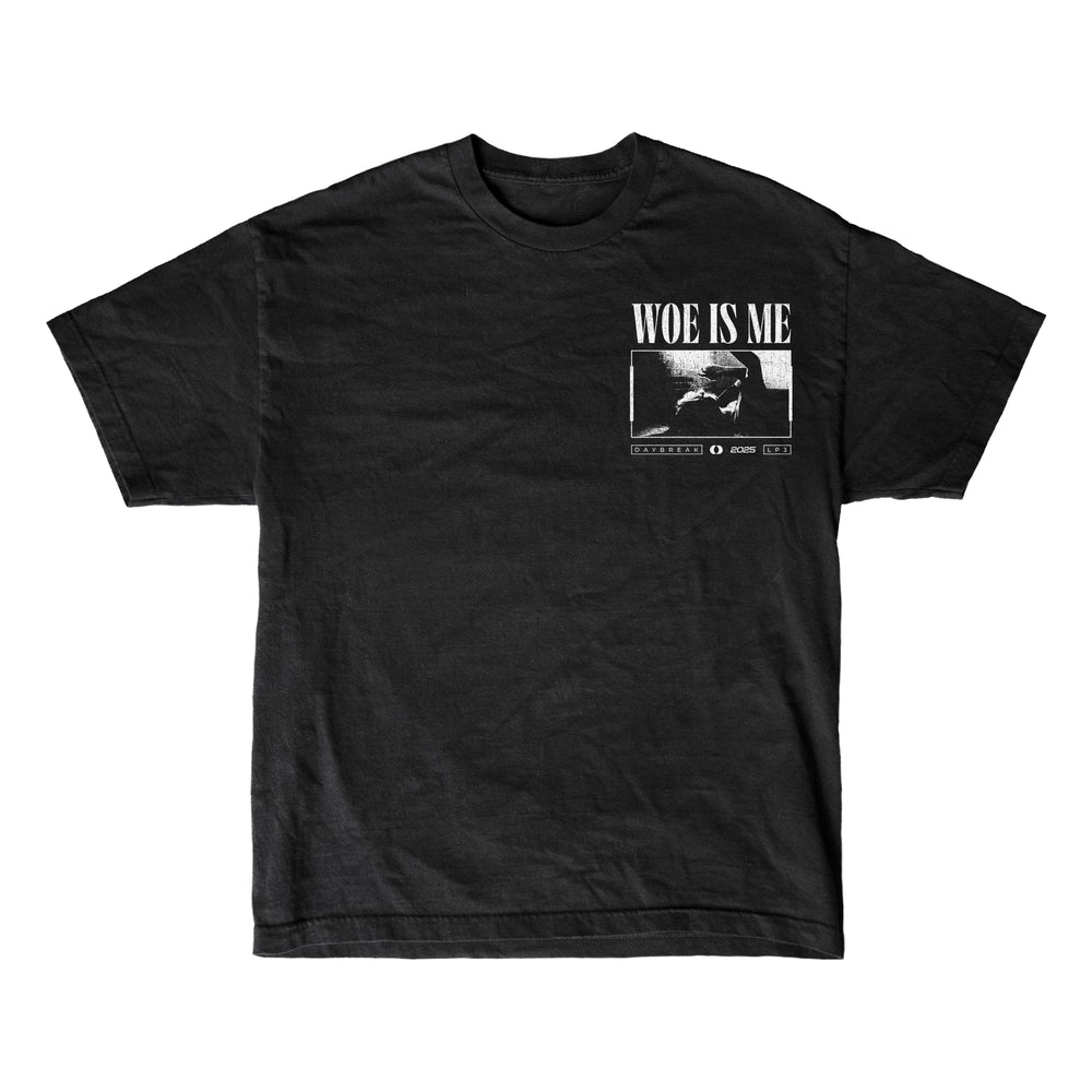 Woe Is Me black t-shirt featuring a small chest graphic of a seated person with WOE IS ME above, referencing LP3. Includes extra white text and design details beneath the image.