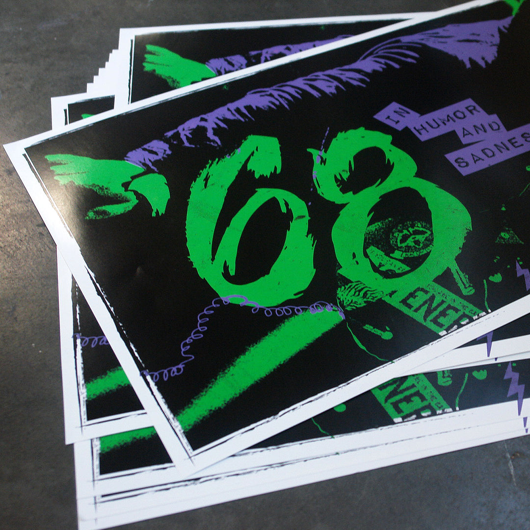 A stack of glossy '68 posters features bold green numbers with abstract purple and black graphics. "HUMOR AND SADNESS" appears in small cut-out text on the top right. The 12x24 posters overlap on a dark surface.