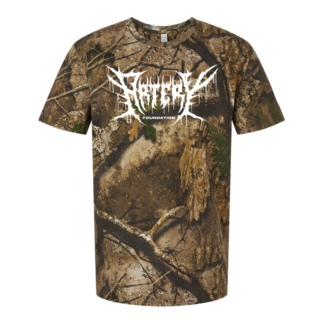 A short-sleeve t-shirt with a brown and green camouflage pattern, featuring rugged REALTREE styling. “ARTERY FOUNDATION” is printed in large, white, jagged letters across the shoulders on the back.