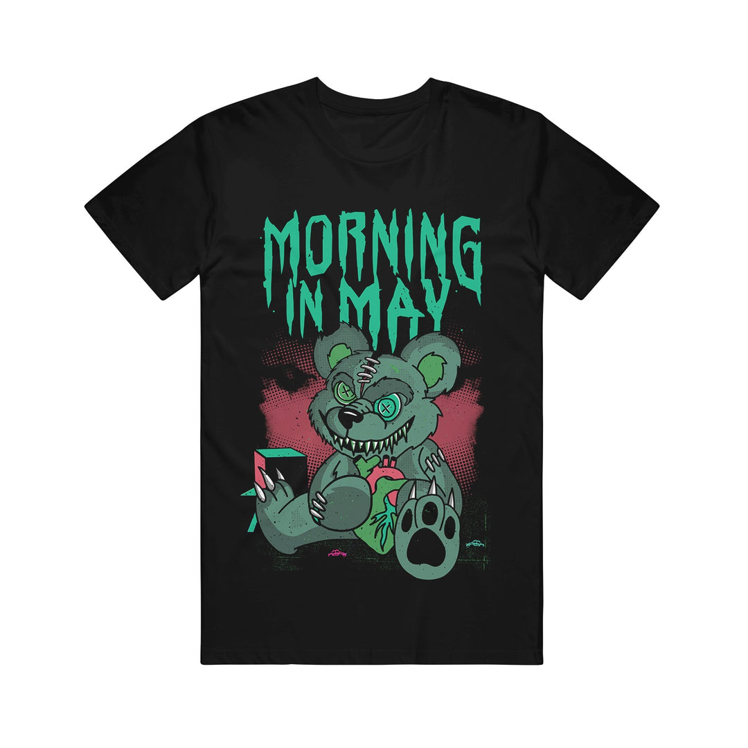 Black graphic tee by Morning In May featuring Deaddy Bear—a green zombie teddy bear with stitches, sharp teeth, and a torn limb. Jagged turquoise "Morning In May" text appears above on a pink splattered background.