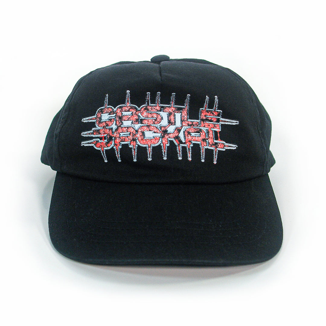 A black Castle Jackal 5-panel Yupoong Classics snapback features jagged red and white embroidered text with spike accents. Displayed on a white background.