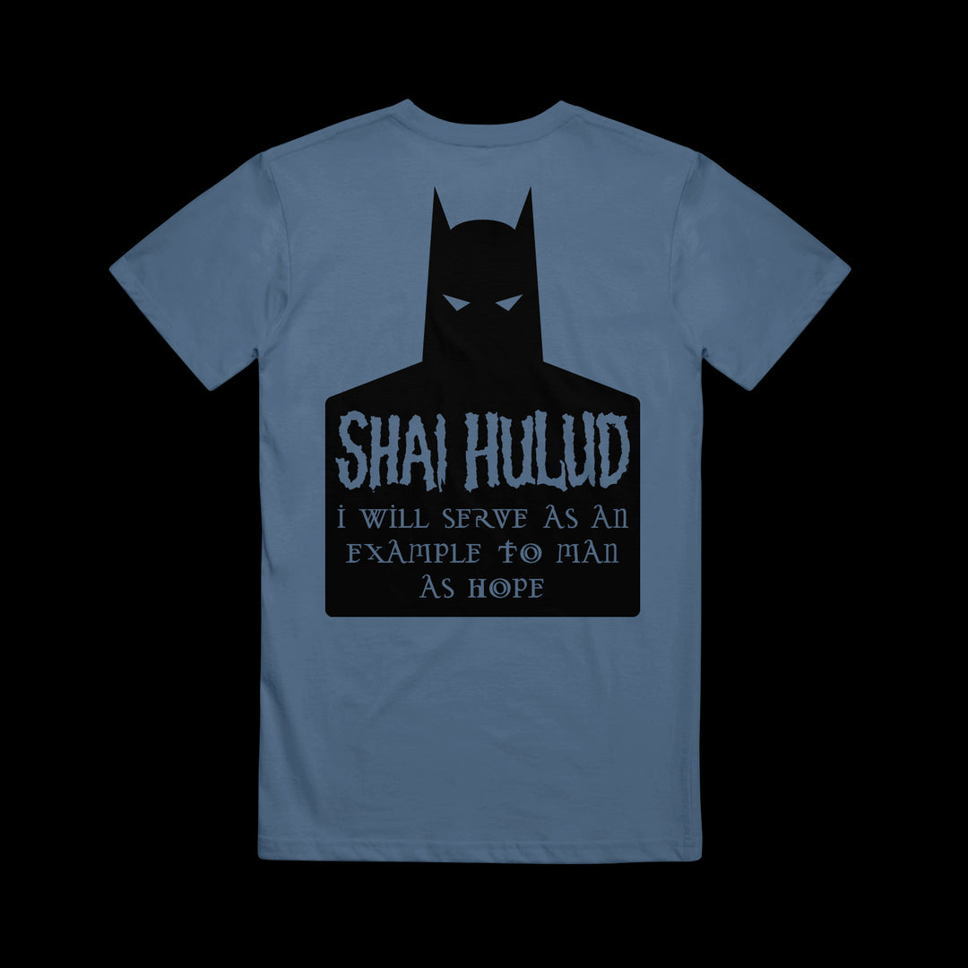 A blue Comfort Colors T-shirt by Shai Hulud features a black Batman silhouette, with “SHAI HULUD” and “I will serve as an example to man as hope” in stylized font on the back—a bold addition to your printed collection.