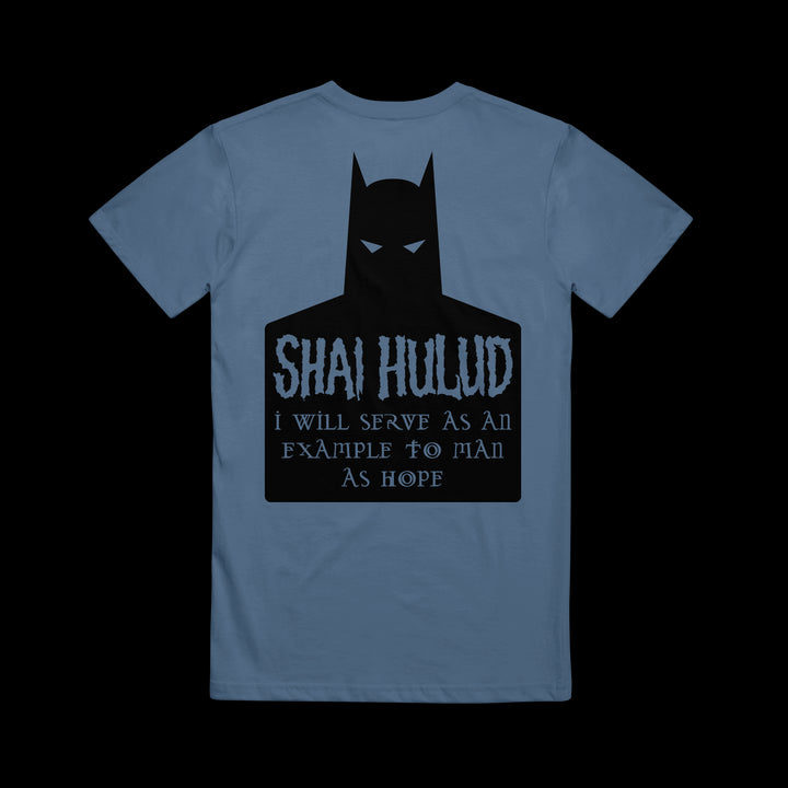 A blue Comfort Colors T-shirt by Shai Hulud features a black Batman silhouette, with “SHAI HULUD” and “I will serve as an example to man as hope” in stylized font on the back—a bold addition to your printed collection.