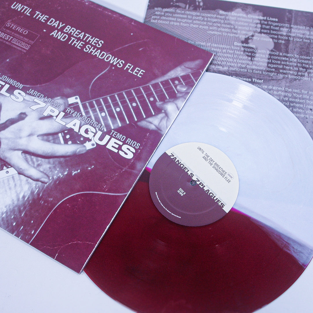 A maroon and white 2 Color Split marbled vinyl by 7 Angels 7 Plagues is partially out of its sleeve, which shows a close-up of hands playing guitar, the album title "7 Plagues," and a partially visible lyrics sheet in the background.