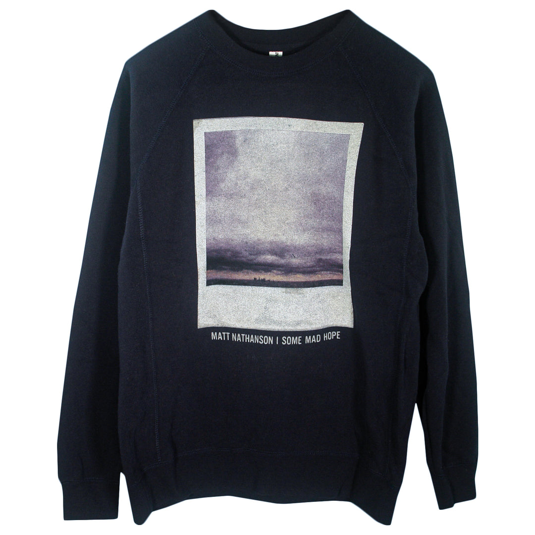 A black Matt Nathanson crewneck sweatshirt featuring a rectangular image of a cloudy sky and horizon, with Matt Nathanson | Some Mad Hope printed below the image.