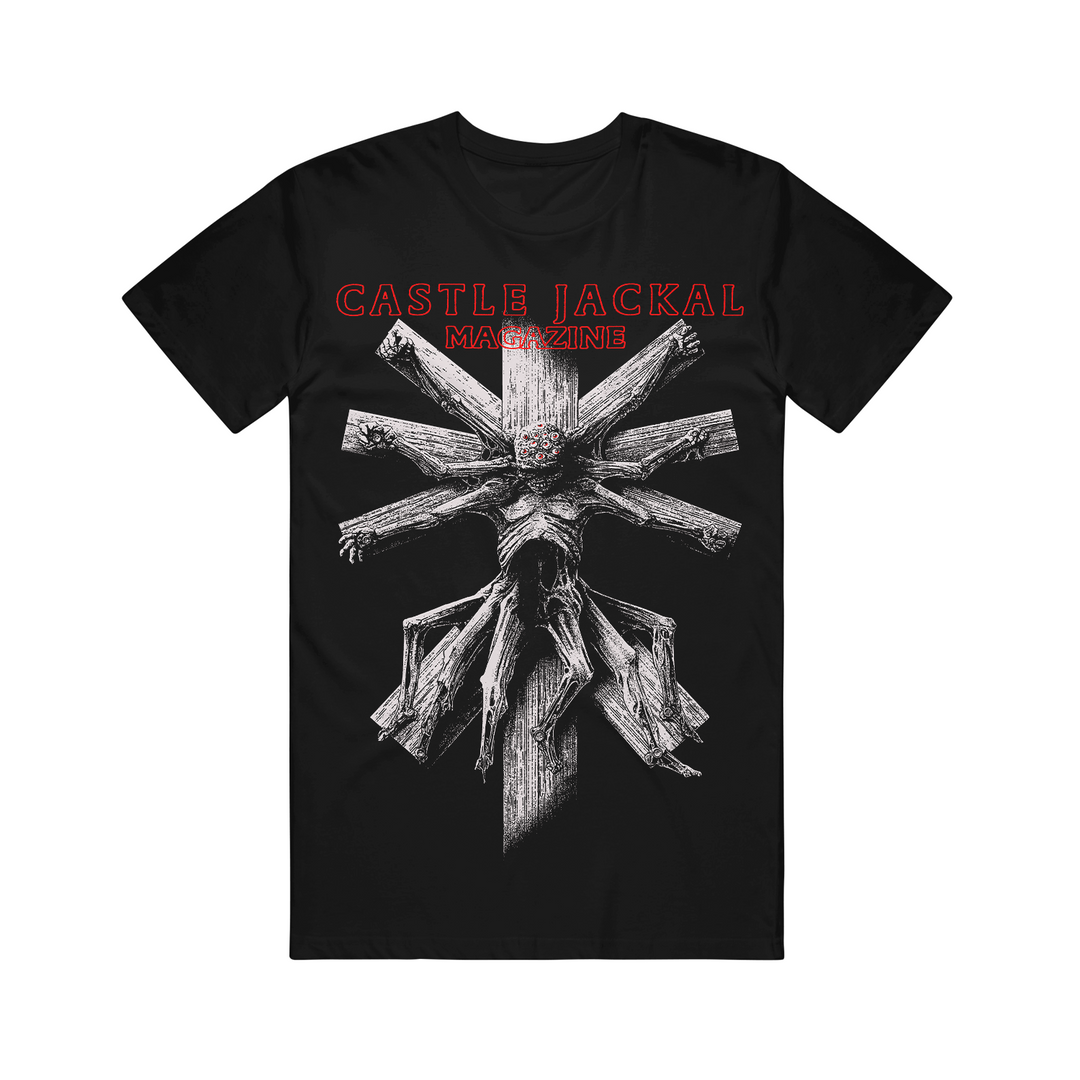 Castle Jackal black Comfort Colors tee with a detailed white wooden cross, skeletal gnarled hands/limbs, and bold red "CASTLE JACKAL MAGAZINE" text above.