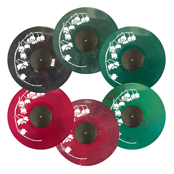 Six colored recycled vinyl records by No Division—green, black, and red—are arranged in two rows. Each features a white lily of the valley floral design near the edge.