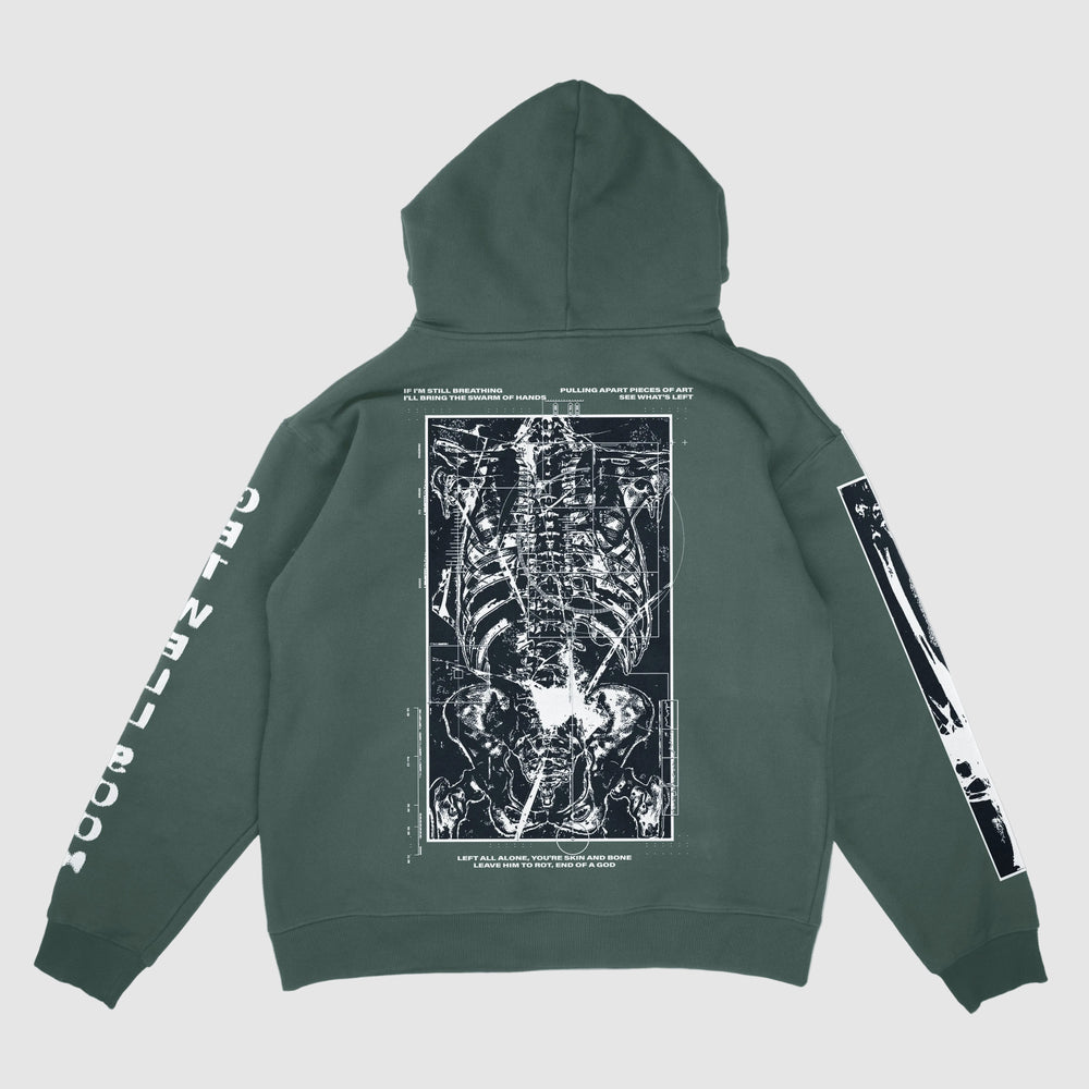 A Johnny Booth forest green Comfort Colors hoodie with a bold white anatomical X-ray skeleton print on the back, surrounded by white text and diagrams, plus matching garment graphics and text printed along both sleeves.