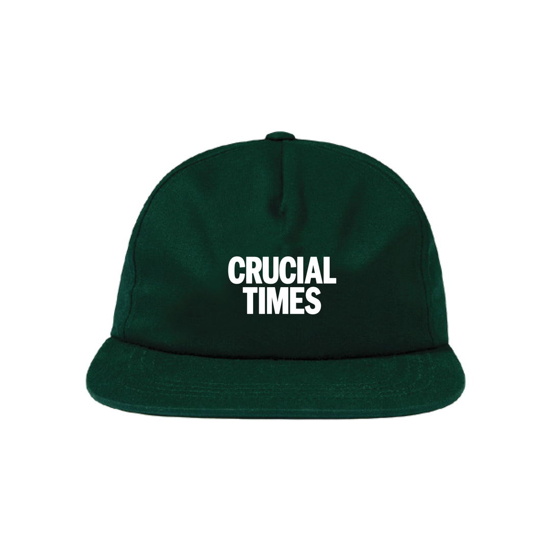 A dark green Crucial Times baseball cap with bold white lettering on the front, displayed on a plain white background. Begins shipping 2/20/26.