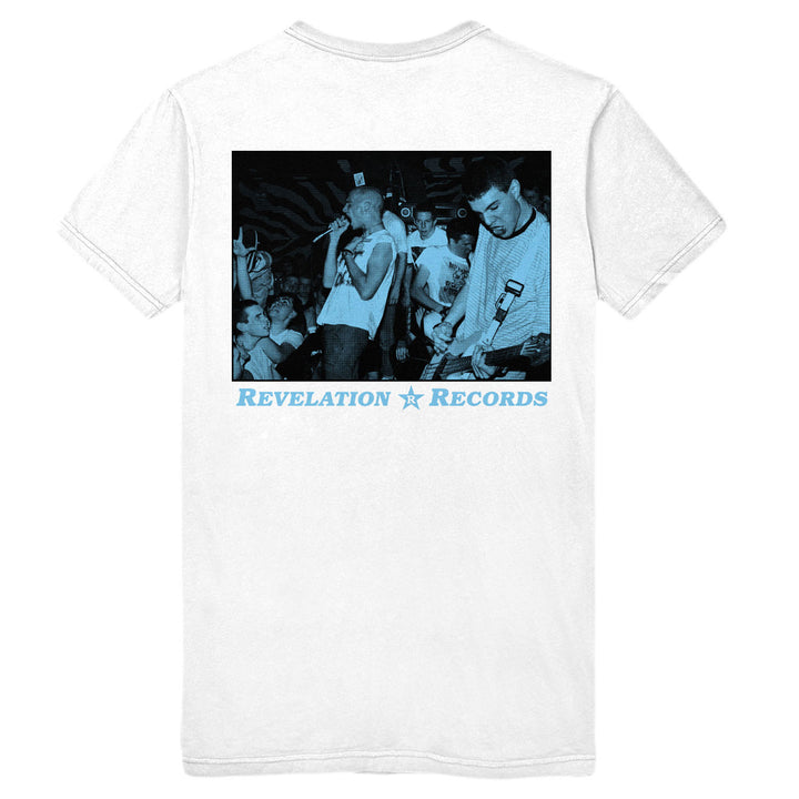 A white Gorilla Biscuits Heavy Cotton T-shirt features a blue-tinted photo of a live band performing for a crowd; below the image, Revelation Records is printed in blue text with a star between the words.
