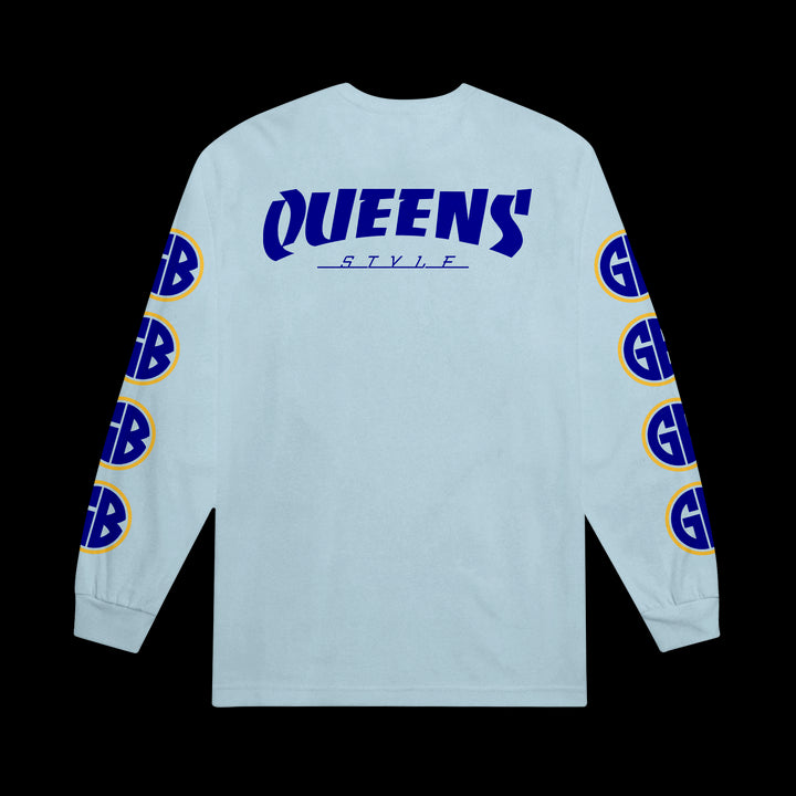 A light blue Gorilla Biscuits Comfort Colors long-sleeve shirt features QUEENS STYLE in bold blue text on the back and yellow-blue GB logos down both sleeves, displayed against a black background.