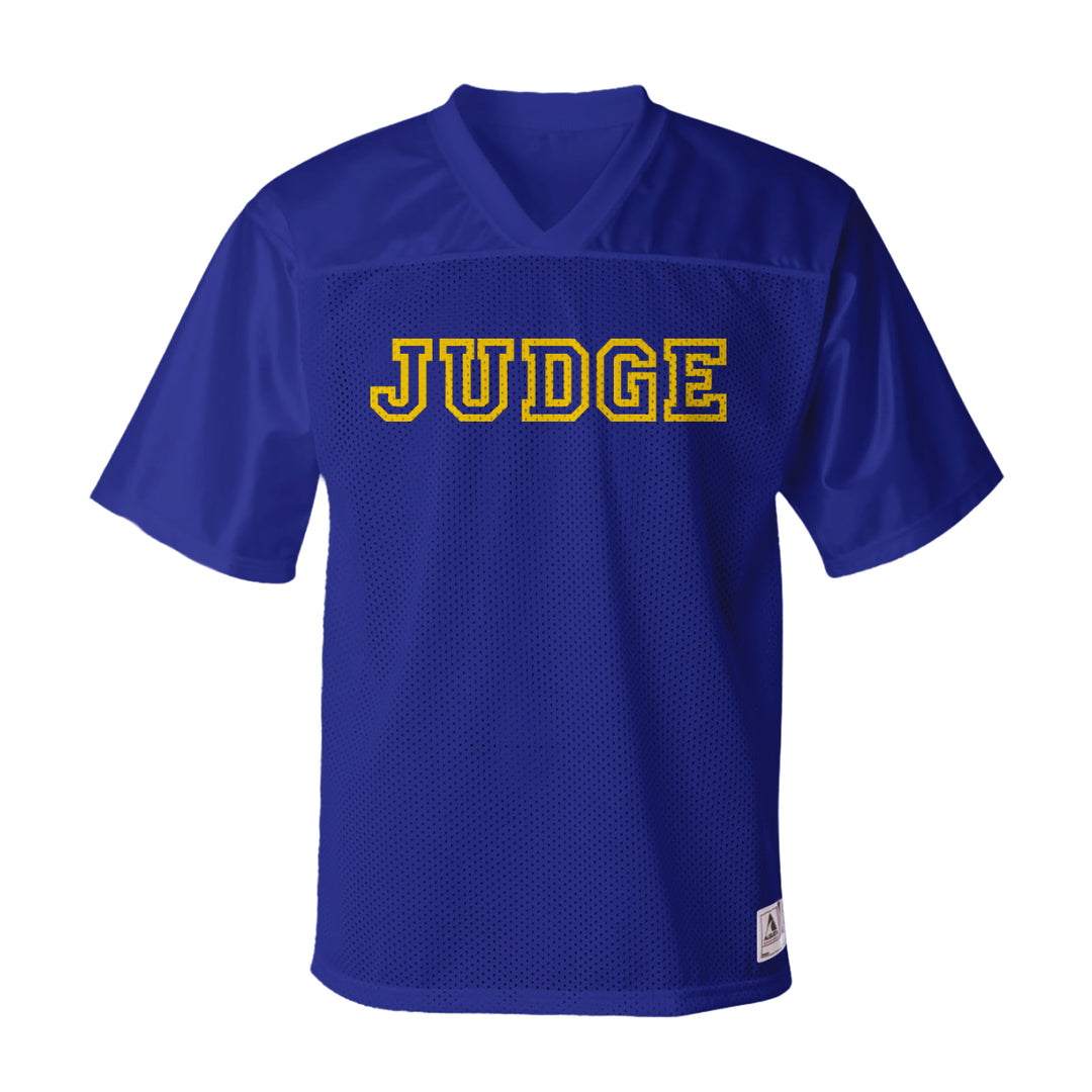 A royal blue Judge sports jersey with short sleeves and a v-neck collar features "JUDGE" in large yellow outlined letters on the chest. Available for presale; shipping begins 11/28/25.