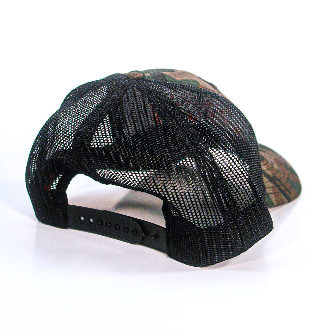 A Skinless camo trucker hat with a camouflage pattern, black mesh back, and adjustable snapback closure is shown on a white background.