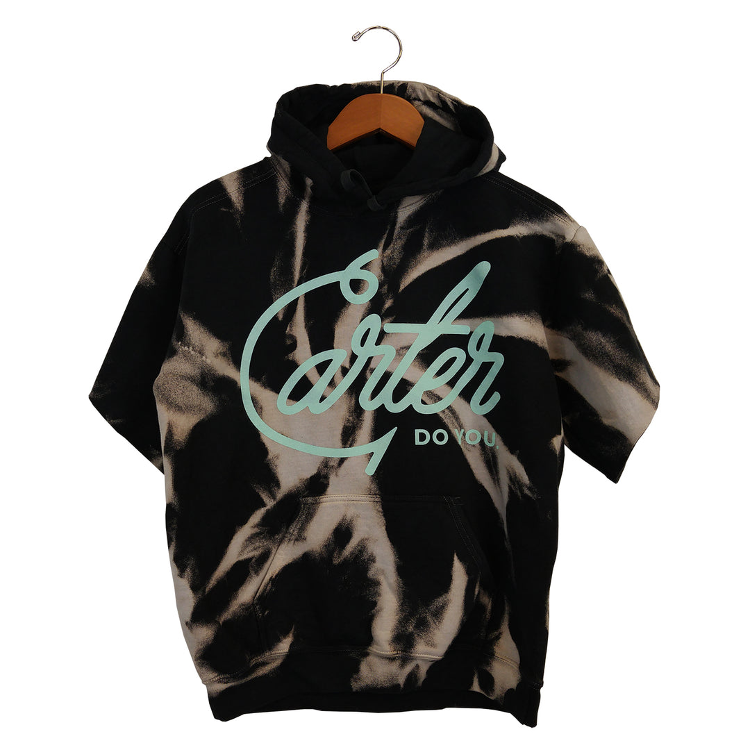 Black and white dyed hooded sweatshirt by Tyler Carter hangs on a hanger, featuring Carter in large light blue cursive and DO YOU below—custom cut for standout style.